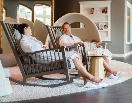 A-ROSA Early Bird A man and a woman in white bathrobes are sitting in rocking chairs.