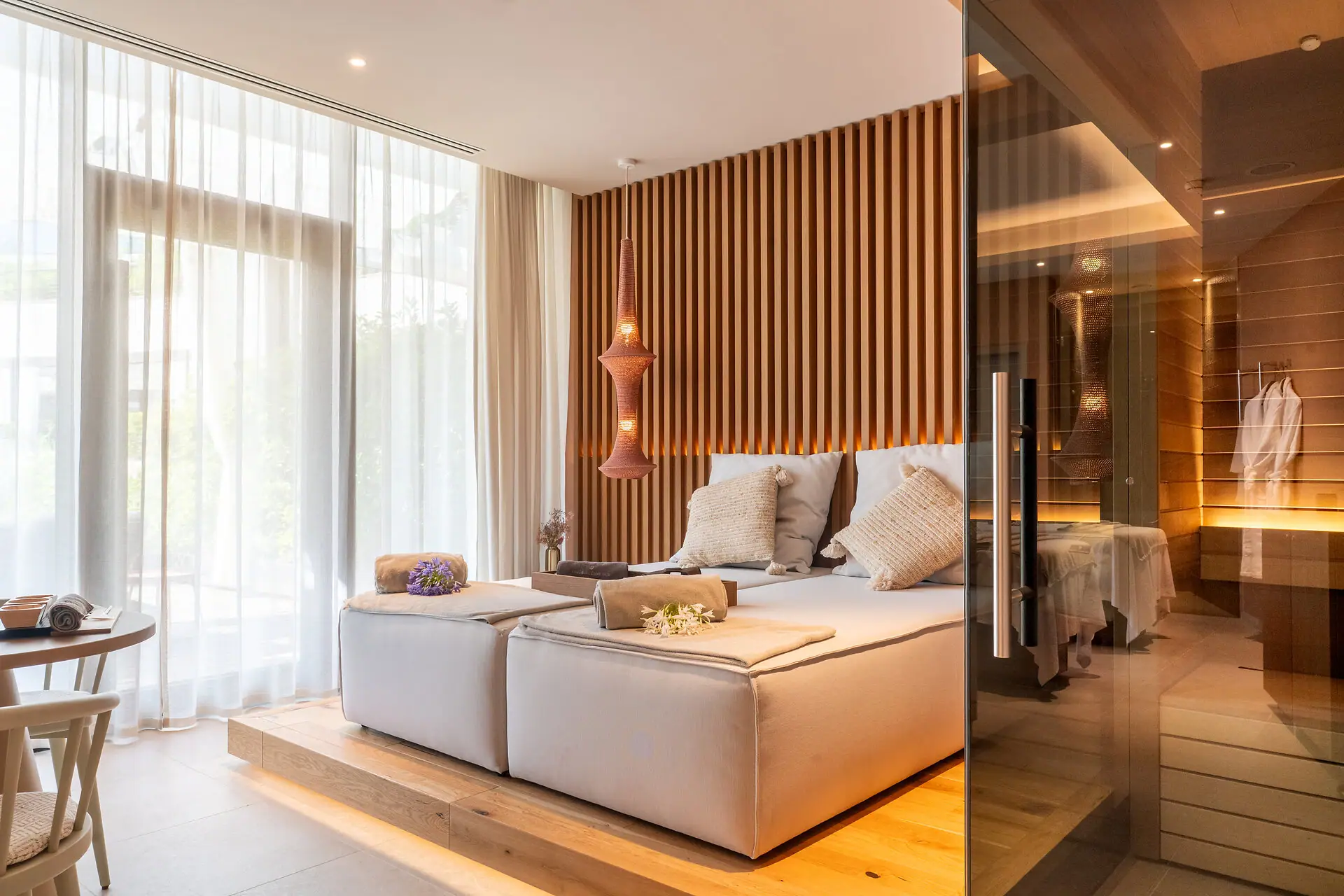 A room with a bed and a glass door, featuring interior design elements like a sofa bed and curtains.