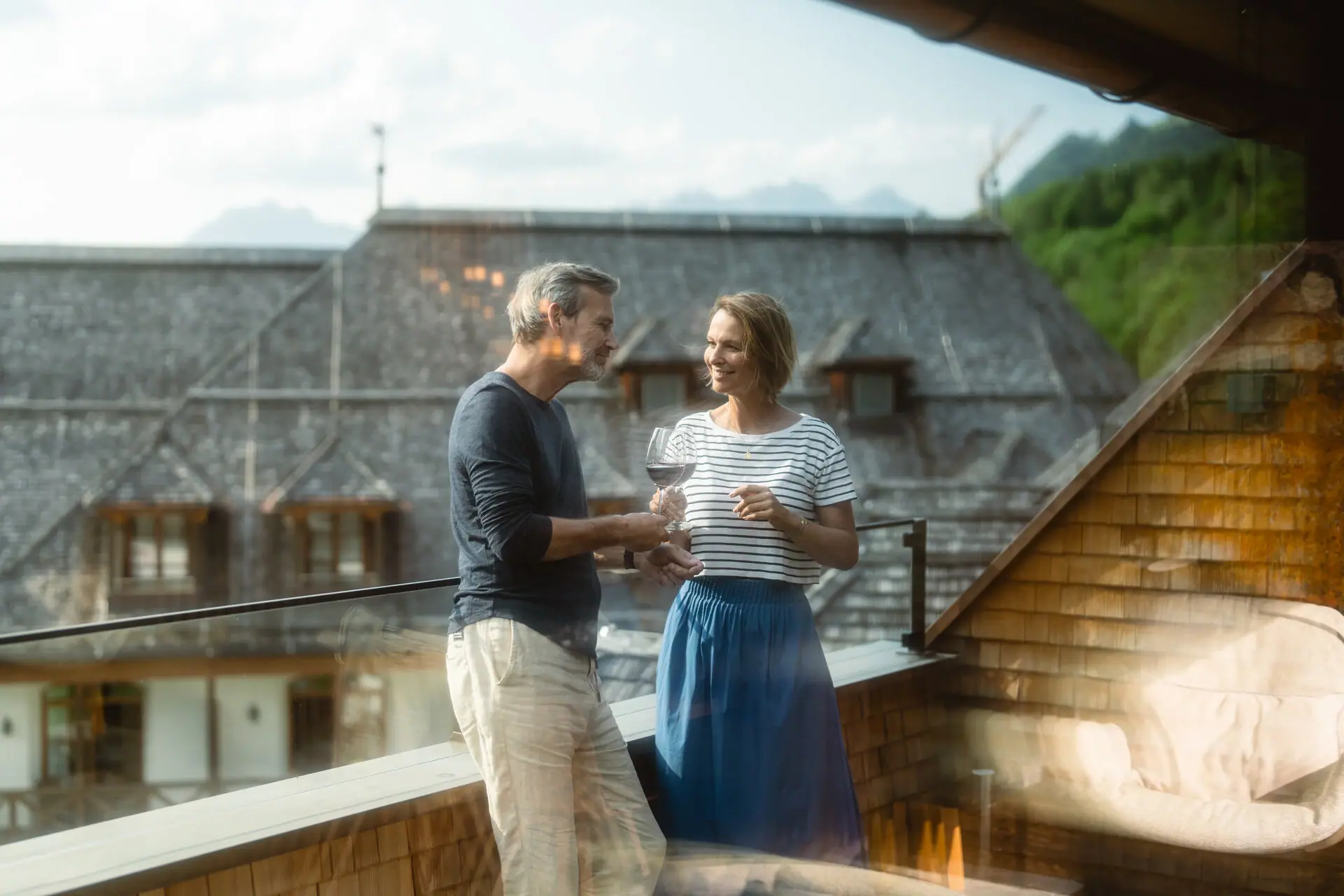 Balkon Ein Mann und eine Frau stehen auf einem Balkon mit Weingläsern.