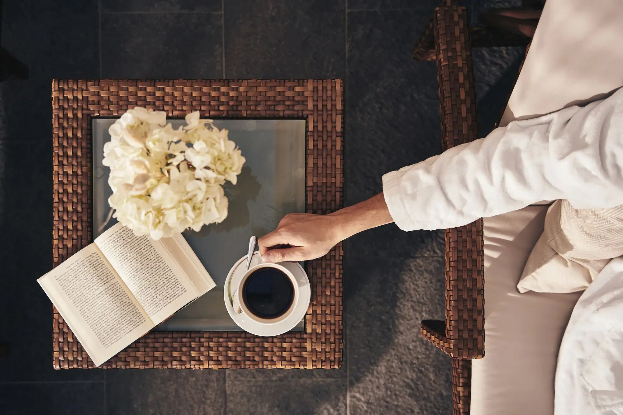 Relaxation room A person is holding a cup of coffee and a book.