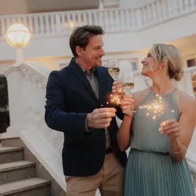 New Year’s Eve packages A man and a woman are holding wine glasses and smiling.