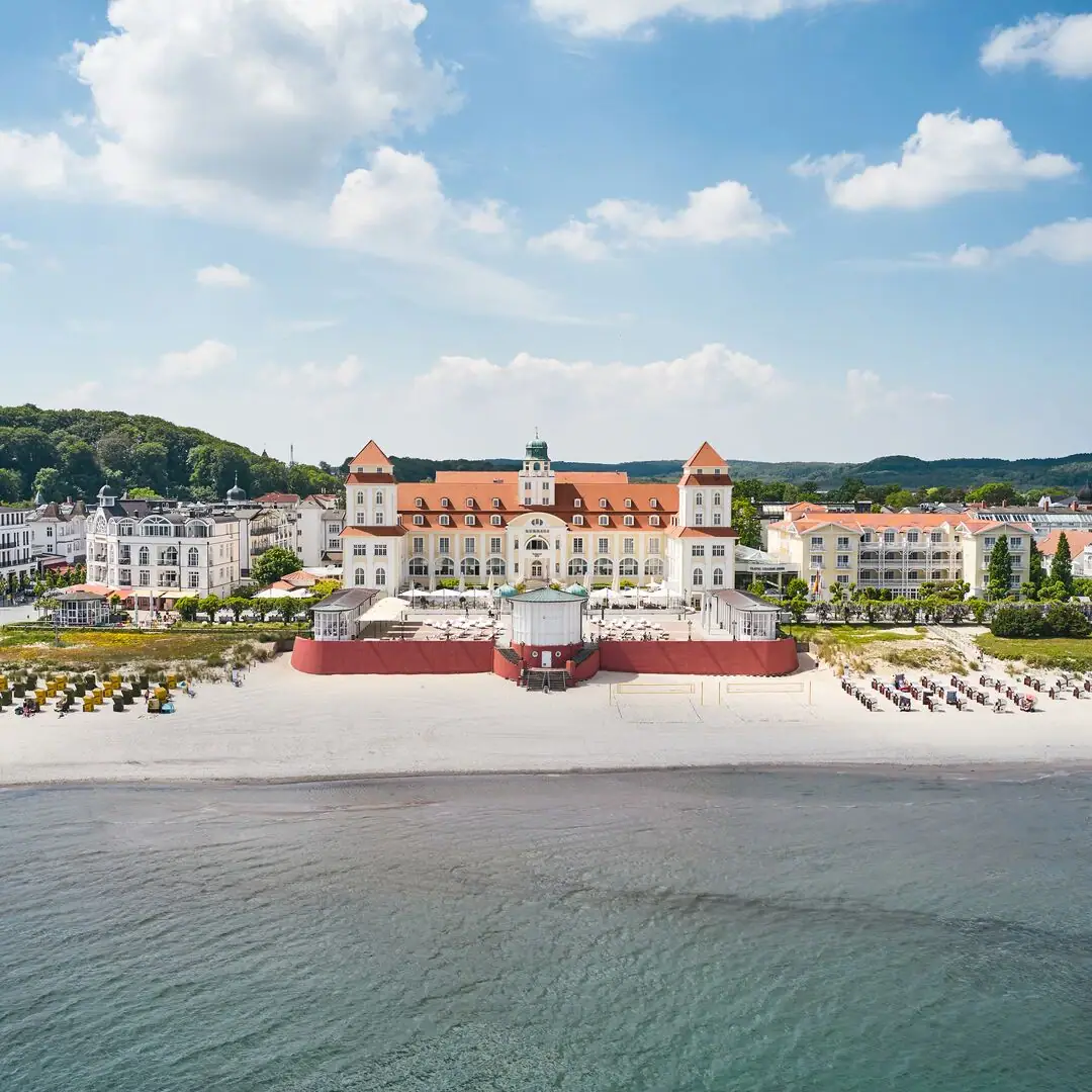 Kurhaus Binz Large building on the beach with a body of water in the foreground.