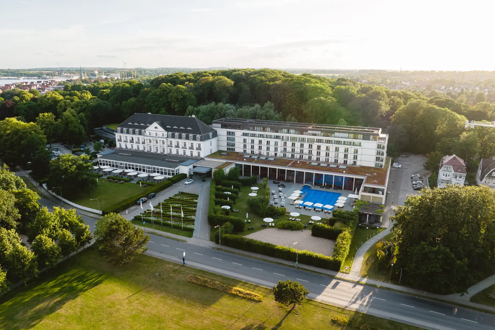 A-ROSA Travemünde A large white building with a pool and trees.