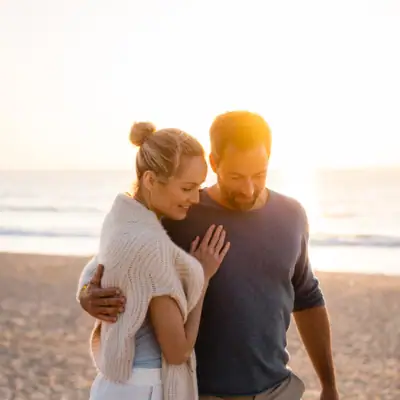 A man and woman sharing a kiss on a beach.