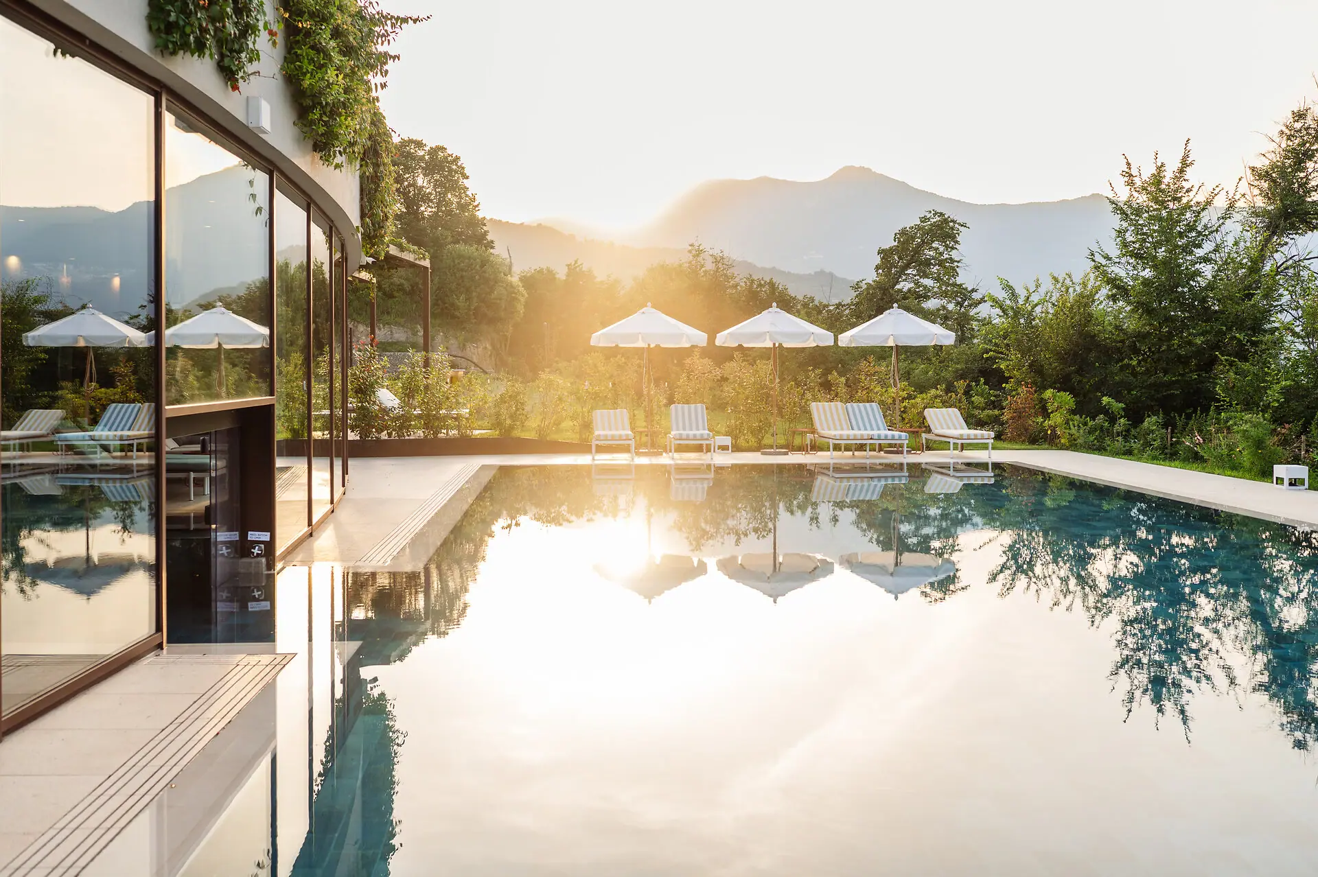 Wellness area A pool with sun loungers and parasols in front of a house.